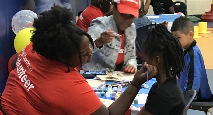 State farm volunteer painting a student&#39;s face