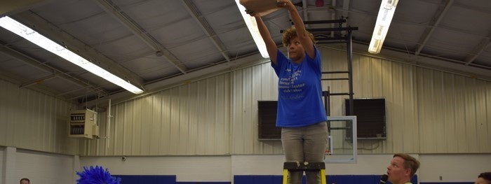 Teacher standing on ladder to demonstrate how strong a STEAM project is